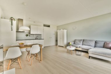 Çağdaş dairenin geniş odasındaki dinlenme odası ve mutfağın yakınındaki sandalyeli ve çiçekli masa.