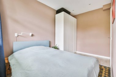 Yatak odasının iç tasarımı, yatak odası ve ahşap gardırop modern dairenin penceresinin kenarına yerleştirilmiş.