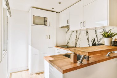 Günümüz minimalist tasarımı. Hafif stüdyo dairesinin ahşap masası ve oturma odası ile beyaz duvarları ve parke zemini arasında yemek masası ve sandalyeleri var.