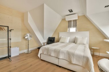 Comfortable bed and furniture in modern minimalist style mansard bedroom with panoramic windows