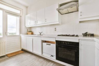 Minimalist tarzı beyaz mobilyalı, lavabolu ve sobalı bir ev mutfağı.