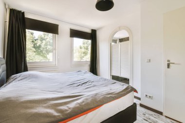 Yatak odasının iç tasarımı, yatak odası ve ahşap gardırop modern dairenin penceresinin kenarına yerleştirilmiş.