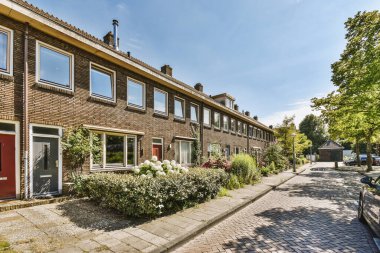 Ağaçlar ve fenerlerle dolu boş bir kaldırım sokağından tuğla evler manzarası