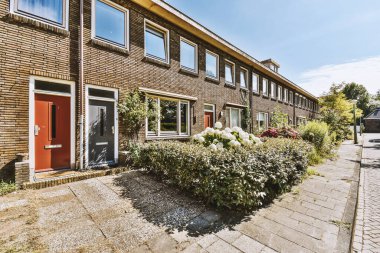 Ağaçlar ve fenerlerle dolu boş bir kaldırım sokağından tuğla evler manzarası