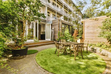 Oturma alanı ve ahşap çitlerin yanındaki küçük bahçesi olan düzgün asfaltlı bir avlu.