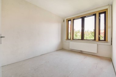 Evdeki boş ışık odasında, beyaz duvardaki plastik pencere ve radyatör.