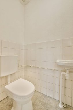 Lavabolu ve duvarlı, beyaz duvarlı ve kareli tuvaletli dar bir tuvalet.