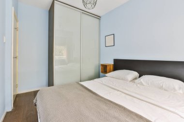 Yatak odasının iç tasarımı, yatak odası ve ahşap gardırop modern dairenin penceresinin kenarına yerleştirilmiş.