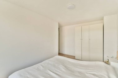 Yatak odasının iç tasarımı, yatak odası ve ahşap gardırop modern dairenin penceresinin kenarına yerleştirilmiş.