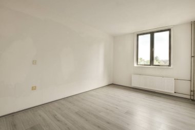 Evdeki boş ışık odasında, beyaz duvardaki plastik pencere ve radyatör.