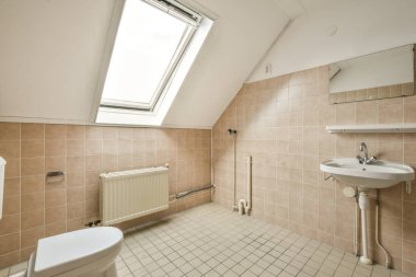 Sink and mirror located near flush toilet and shower against tile wall with window