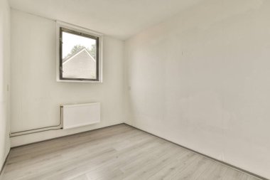 Evdeki boş ışık odasında, beyaz duvardaki plastik pencere ve radyatör.