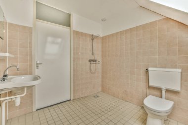 Sink and mirror located near flush toilet and shower against tile wall with window