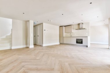 Pencereleri ve ahşap parke zemini olan boş beyaz mutfağın içi.