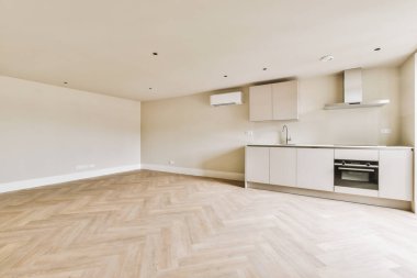 Pencereleri ve ahşap parke zemini olan boş beyaz mutfağın içi.