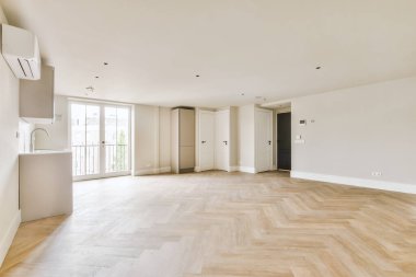 Pencereleri ve ahşap parke zemini olan boş beyaz mutfağın içi.