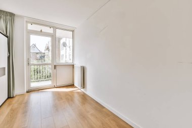 Evdeki boş ışık odasında, beyaz duvardaki plastik pencere ve radyatör.