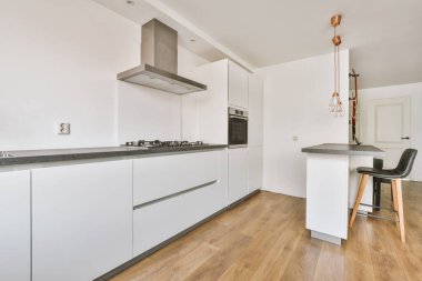 Günümüz minimalist tasarımı. Hafif stüdyo dairesinin ahşap masası ve oturma odası ile beyaz duvarları ve parke zemini arasında yemek masası ve sandalyeleri var.