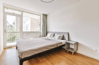 Yatak odasının iç tasarımı, yatak odası ve ahşap gardırop modern dairenin penceresinin kenarına yerleştirilmiş.