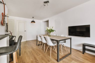 Günümüz minimalist tasarımı. Hafif stüdyo dairesinin ahşap masası ve oturma odası ile beyaz duvarları ve parke zemini arasında yemek masası ve sandalyeleri var.