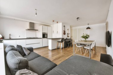 Günümüz minimalist tasarımı. Hafif stüdyo dairesinin ahşap masası ve oturma odası ile beyaz duvarları ve parke zemini arasında yemek masası ve sandalyeleri var.