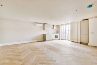 Pencereleri ve ahşap parke zemini olan boş beyaz mutfağın içi.