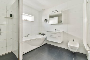 Modern banyo. Dikdörtgen aynası ve temiz lavaboları modern banyo odasındaki duş kabininin yanındaki beyaz fayanslı duvara bağlı.