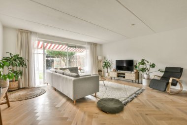 Çağdaş dairenin geniş odasındaki dinlenme odası ve mutfağın yakınındaki sandalyeli ve çiçekli masa.