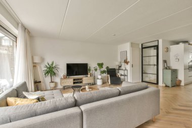 Çağdaş dairenin geniş odasındaki dinlenme odası ve mutfağın yakınındaki sandalyeli ve çiçekli masa.