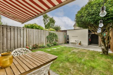 Neat powerful patio with sitting area and small garden near wooden fence
