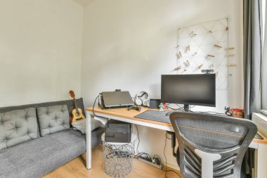 Comfortable sofa placed near table with computer monitors in contemporary flat