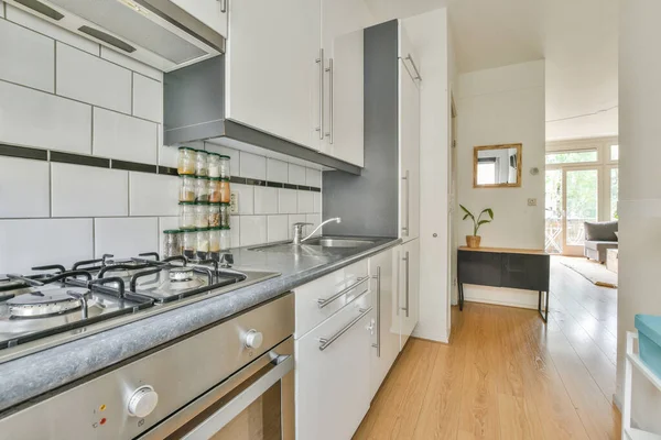 Contemporary counters and stools located under stylish exhaust hood in spacious light kitchen at home