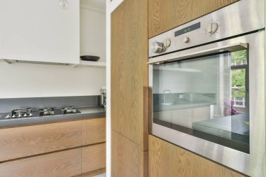 Çağdaş dairenin geniş odasındaki dinlenme odası ve mutfağın yakınındaki sandalyeli ve çiçekli masa.