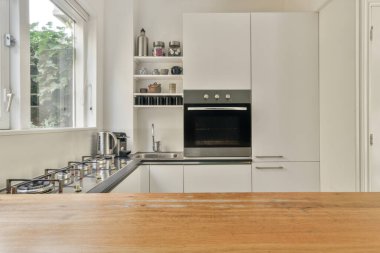 Çağdaş dairenin geniş odasındaki dinlenme odası ve mutfağın yanındaki sandalyeli masa.