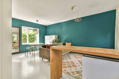 Çağdaş dairenin geniş odasındaki dinlenme odası ve mutfağın yanındaki sandalyeli masa.