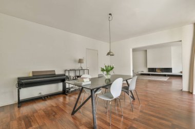 table with vase and chairs placed near opened balcony door in light living room at home