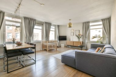 Table with chairs and sofa near lounge area ,kitchen and washing machine in spacious room of contemporary apartment