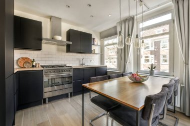 Table with chairs and sofa near lounge area ,kitchen and washing machine in spacious room of contemporary apartment