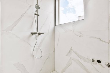 Duş muslukları cam bölmenin yanındaki fayanslı duvara bağlı ve evdeki tuvaletteki süs pervazı.