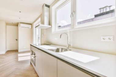 Minimalist tarzı beyaz mobilyalı, lavabolu ve sobalı bir ev mutfağı.