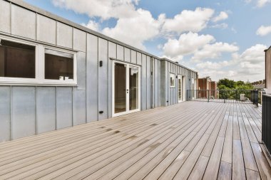 Bright wooden balcony with metal railings and door