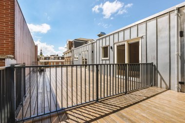 Bright wooden balcony with metal railings and door