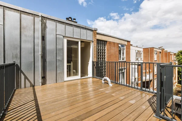 Bright wooden balcony with metal railings and door
