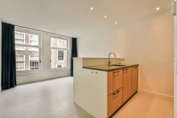 Contemporary counters and stools located under stylish exhaust hood in spacious light kitchen at home