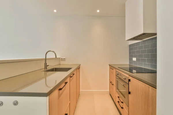 Contemporary counters and stools located under stylish exhaust hood in spacious light kitchen at home