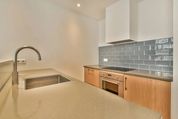 Contemporary counters and stools located under stylish exhaust hood in spacious light kitchen at home