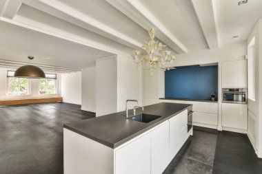 Interior of light kitchen with modern cupboards and appliances located near living room in modern flat at daytime