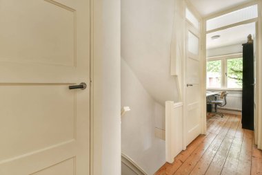 Dar koridorun içinde, merdivenin ve evin koridorundaki çalışma odasına açılan beyaz duvarlı bir sürü kapı var.