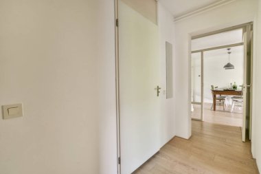 Interior of narrow corridor with telephone and many doors in daylight