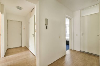 Interior of narrow corridor with telephone and many doors in daylight